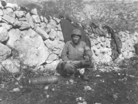 A soldier squats next to a mortar shell in Italy, 1944. [Courtesy of Mary Hamasaki]