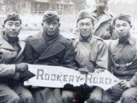 5 soldiers at pier holding sign "Rookery Road".  Kazuo Yamane seated on the far right.  [Courtesy of James Nogawa]