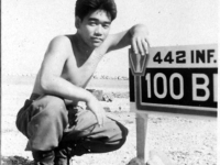 Tamura poses with the 442nd/100th Battalion sign in Italy [Courtesy of Robert Arakaki]