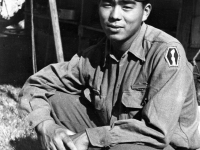 Jimmy Inafuku squatting in front of tent, Lecco, Italy, 1945 [Courtesy of Carol Inafuku]