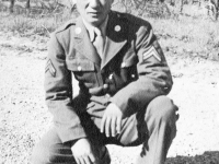 James Kawashima squatting in front of bare trees at Camp McCoy, Wisconsin [Courtesy of Alexandra Nakamura]